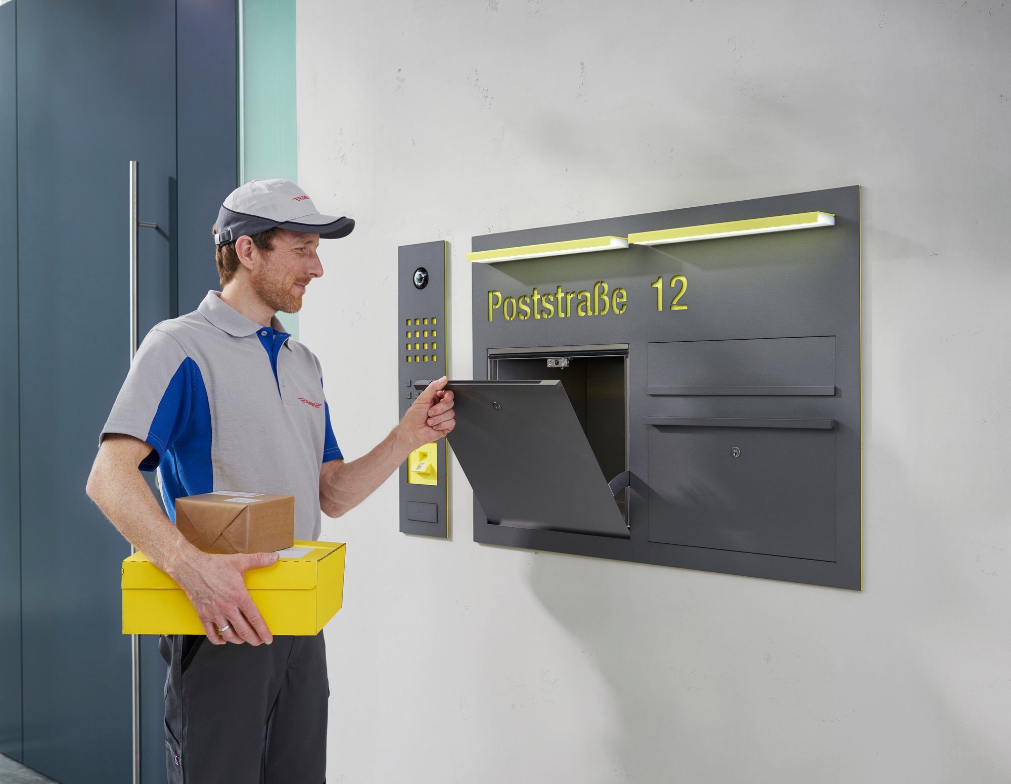 Paketbote legt eine Sendung in eine Siedle-Lieferbox mit integrierter Türkommunikation